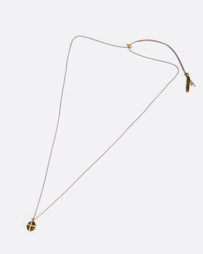 A Japanese river pebble pendant wrapped in yellow gold and hanging from a cord, shown from the front.