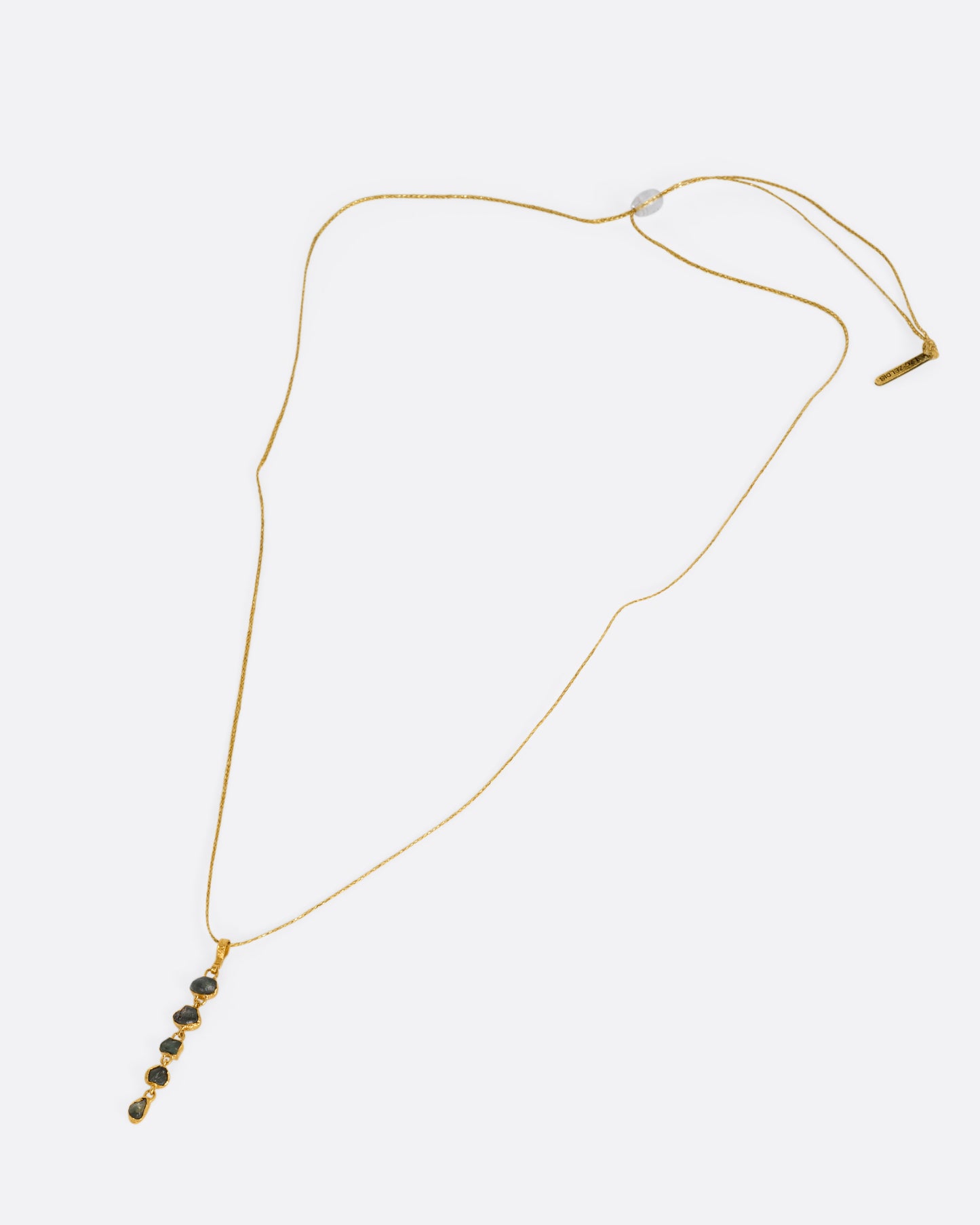 A yellow gold pendant with five Montana sapphires on a cord, shown from the front.