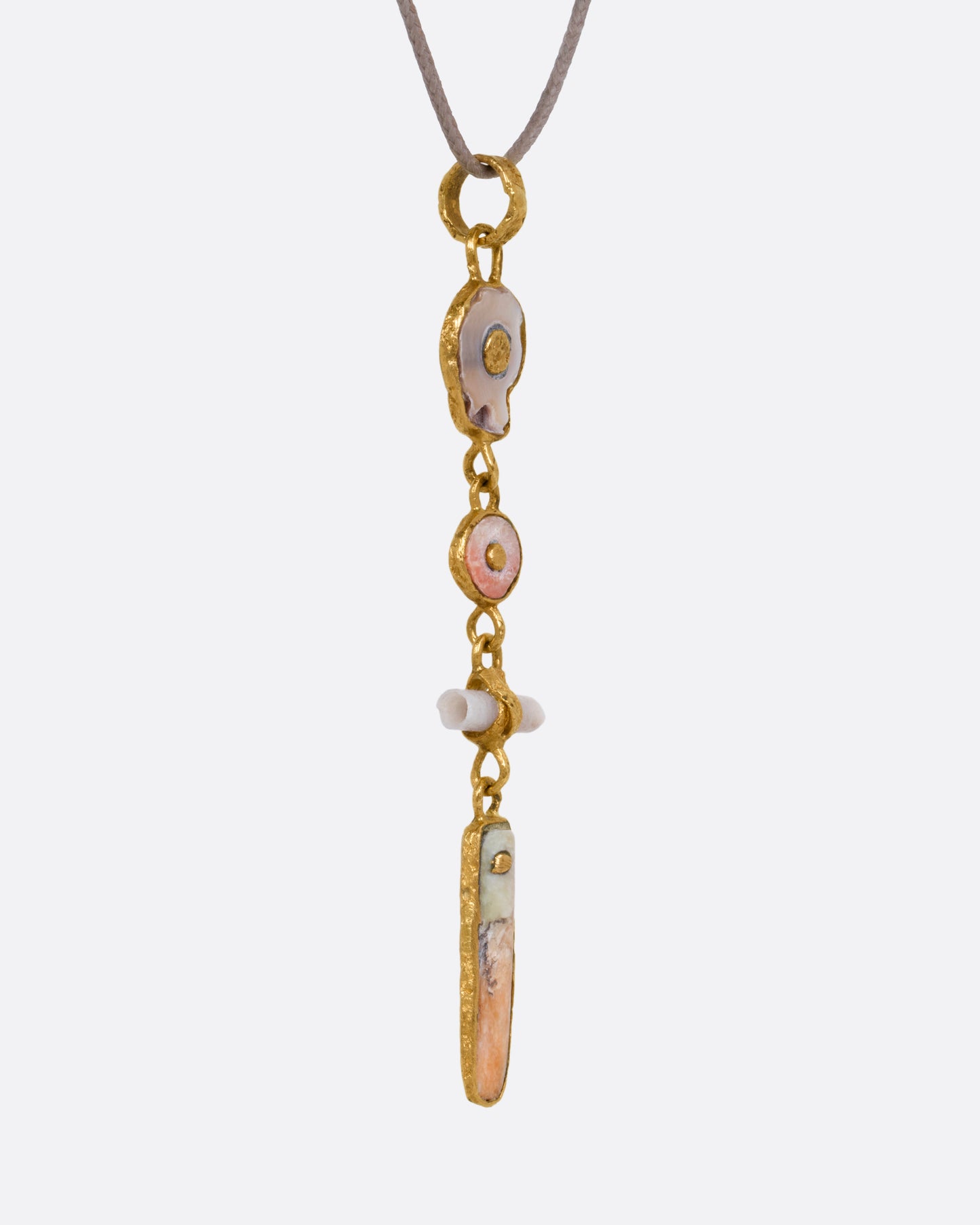 A yellow gold pendant with four gold wrapped pieces on a cord, shown from the side.