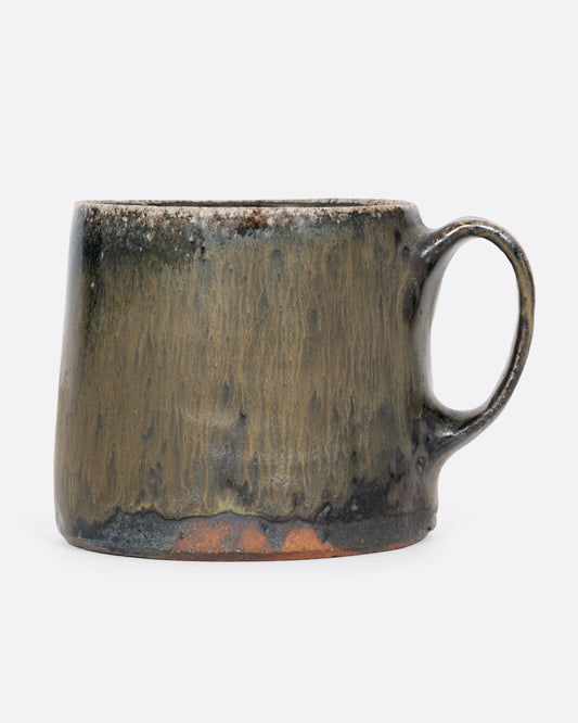 A hand thrown ceramic mug in blues and earthy greens. Shown from the side.