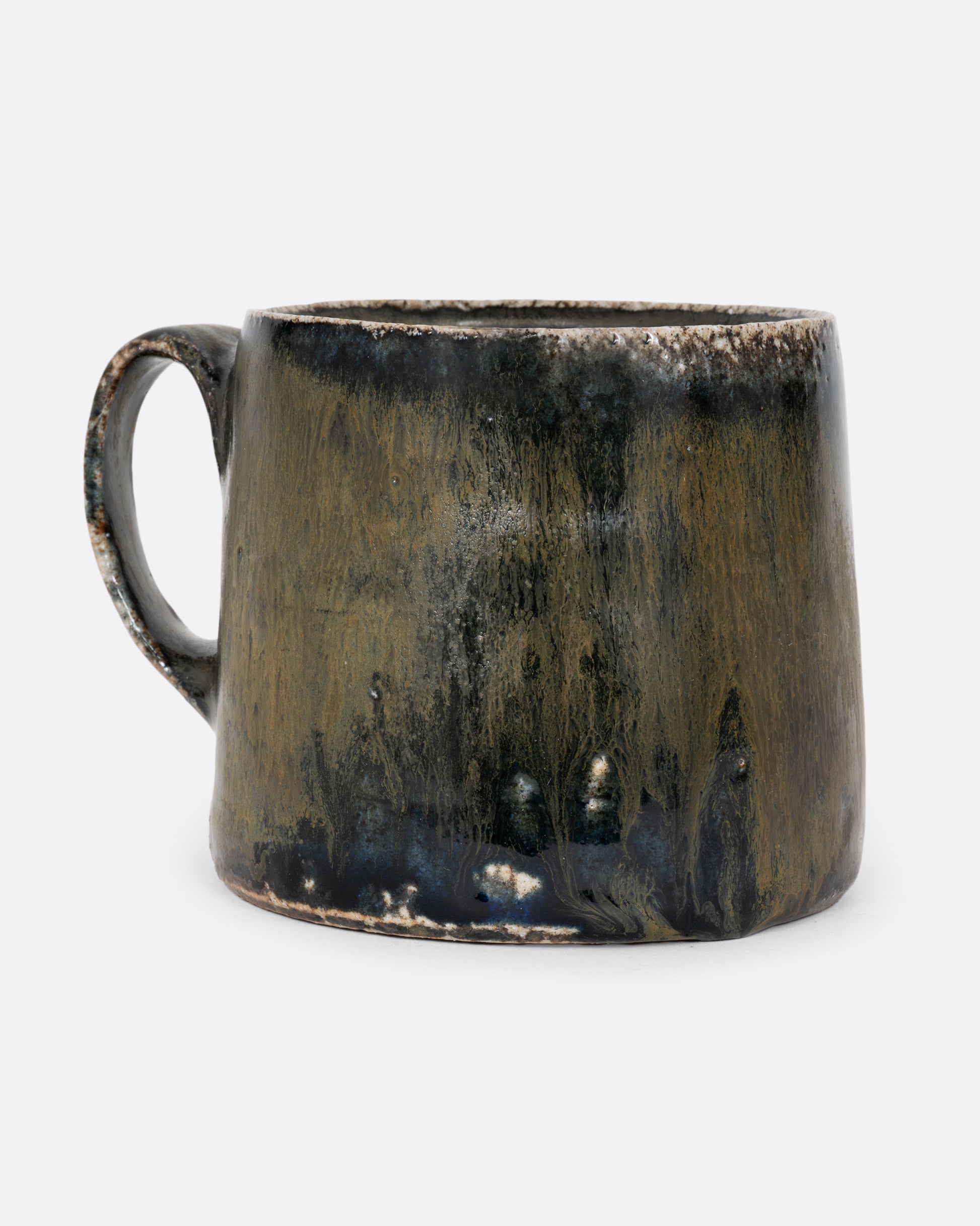 A hand thrown ceramic mug in blues and earthy greens. Shown from the front.