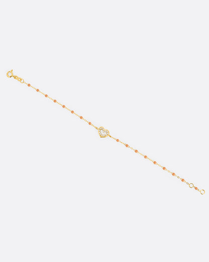 A yellow gold cable chain bracelet with a diamond lined heart charm and caramel brown resin droplets throughout. Shown from the front.