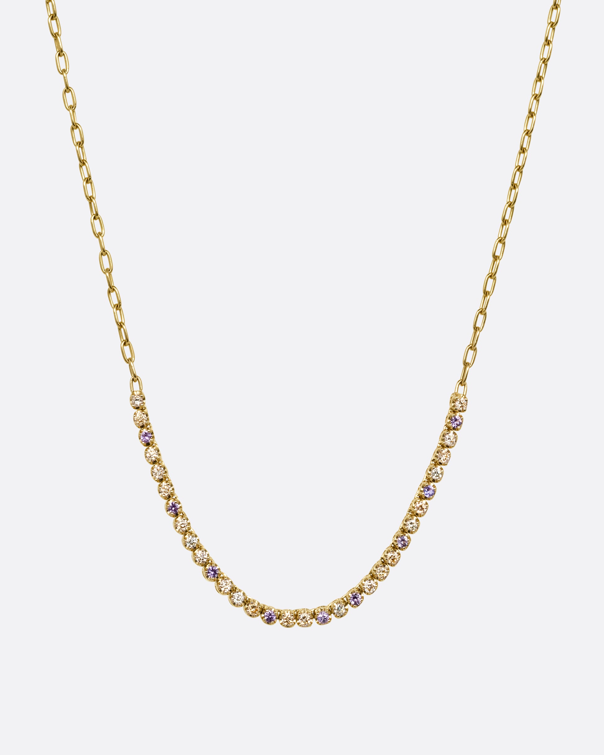 A yellow gold cable chain necklace with peach and yellow diamonds and purple sapphires in a 'partial tennis' setting. Shown from the front.