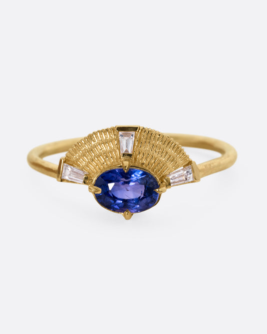A yellow gold ring with a purple sapphire and three baguette diamonds, shown from the front.