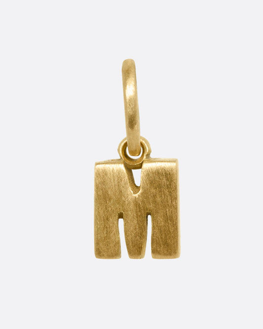 A yellow gold letter 'M' pendant shown from the front.