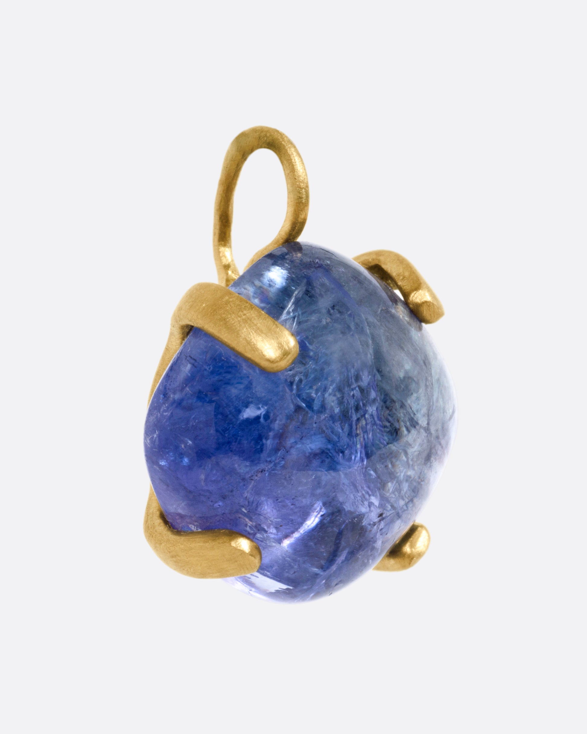 A yellow gold charm with a prong set tanzanite cabochon, shown from the side.