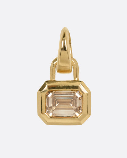 A yellow gold charm with a step cut champagne diamond, shown from the front.
