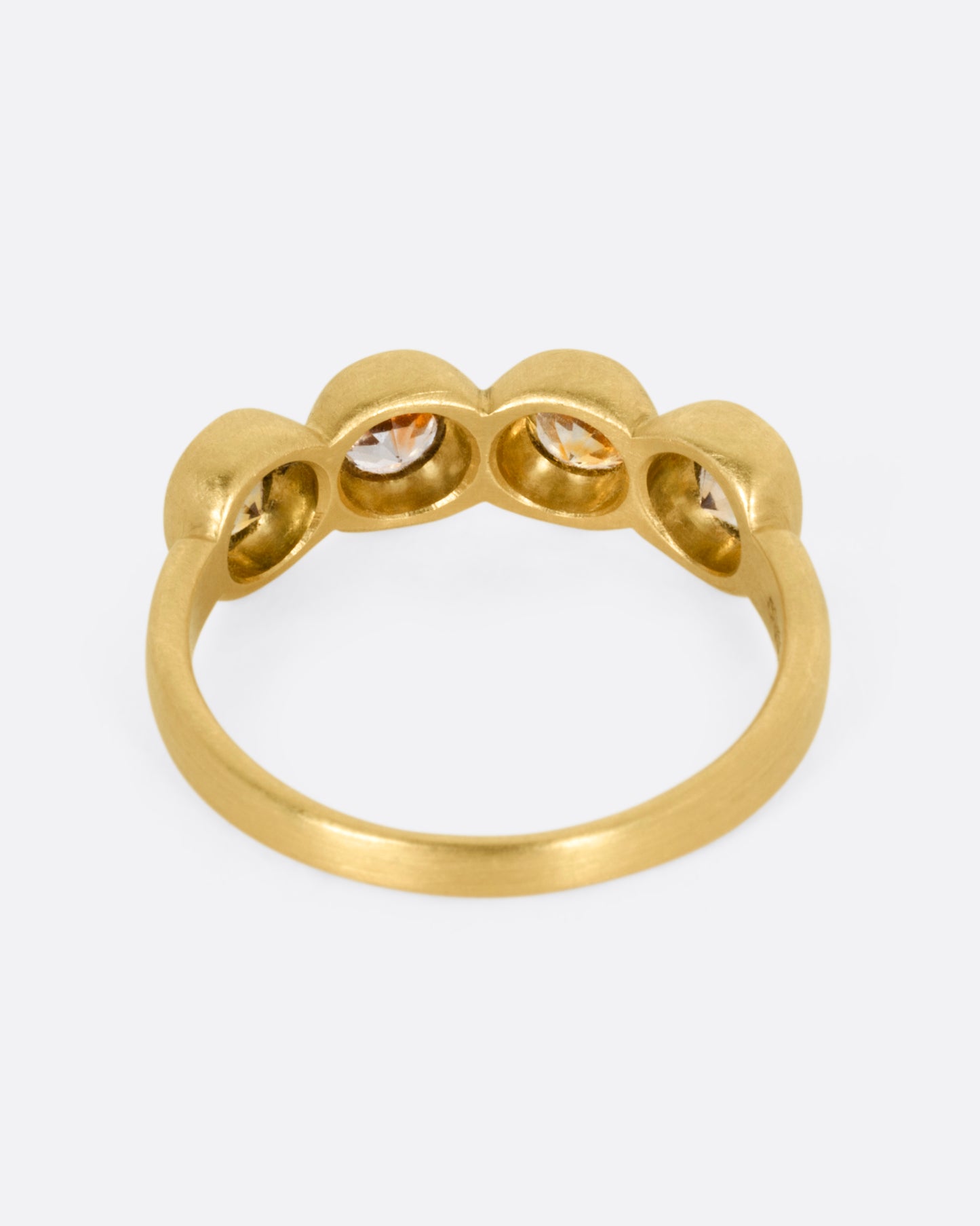 A yellow gold ring with four bezel set kaleidoscope sapphires, shown from the back.
