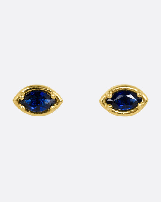 A pair of yellow gold eye shaped earrings with marquise blue sapphires. Shown from the front.