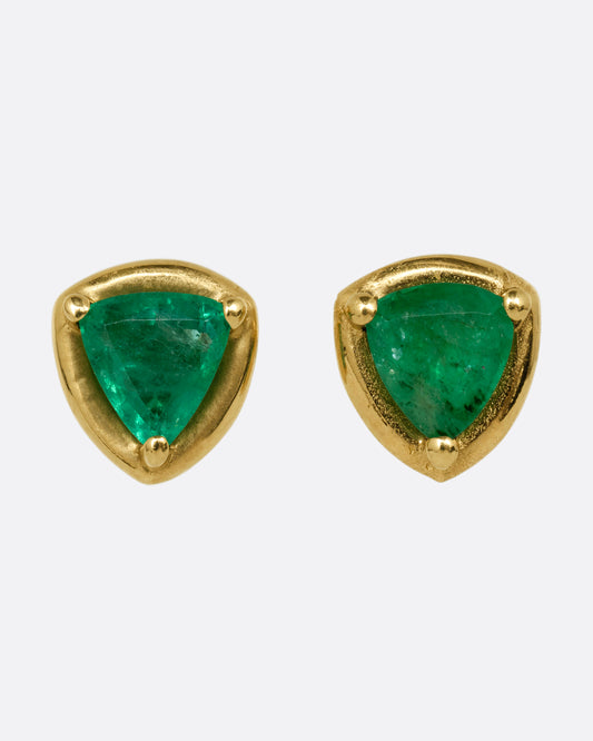 A pair of yellow gold stud earrings with emeralds. Shown from the front.