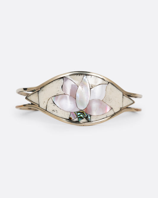 An alpaca silver cuff bracelet with a pink mother of pearl and abalone lotus on its face. Shown from the front. 