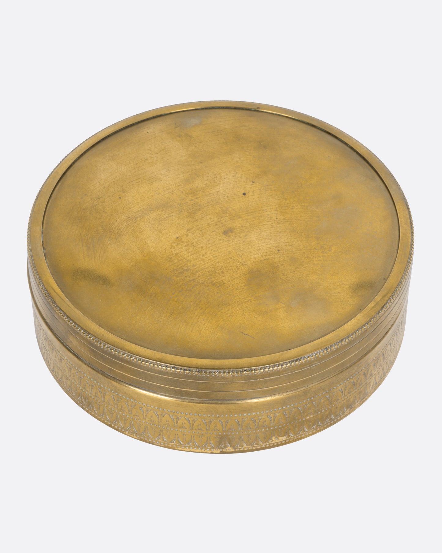 A circular brass box with a lid, shown from the top.