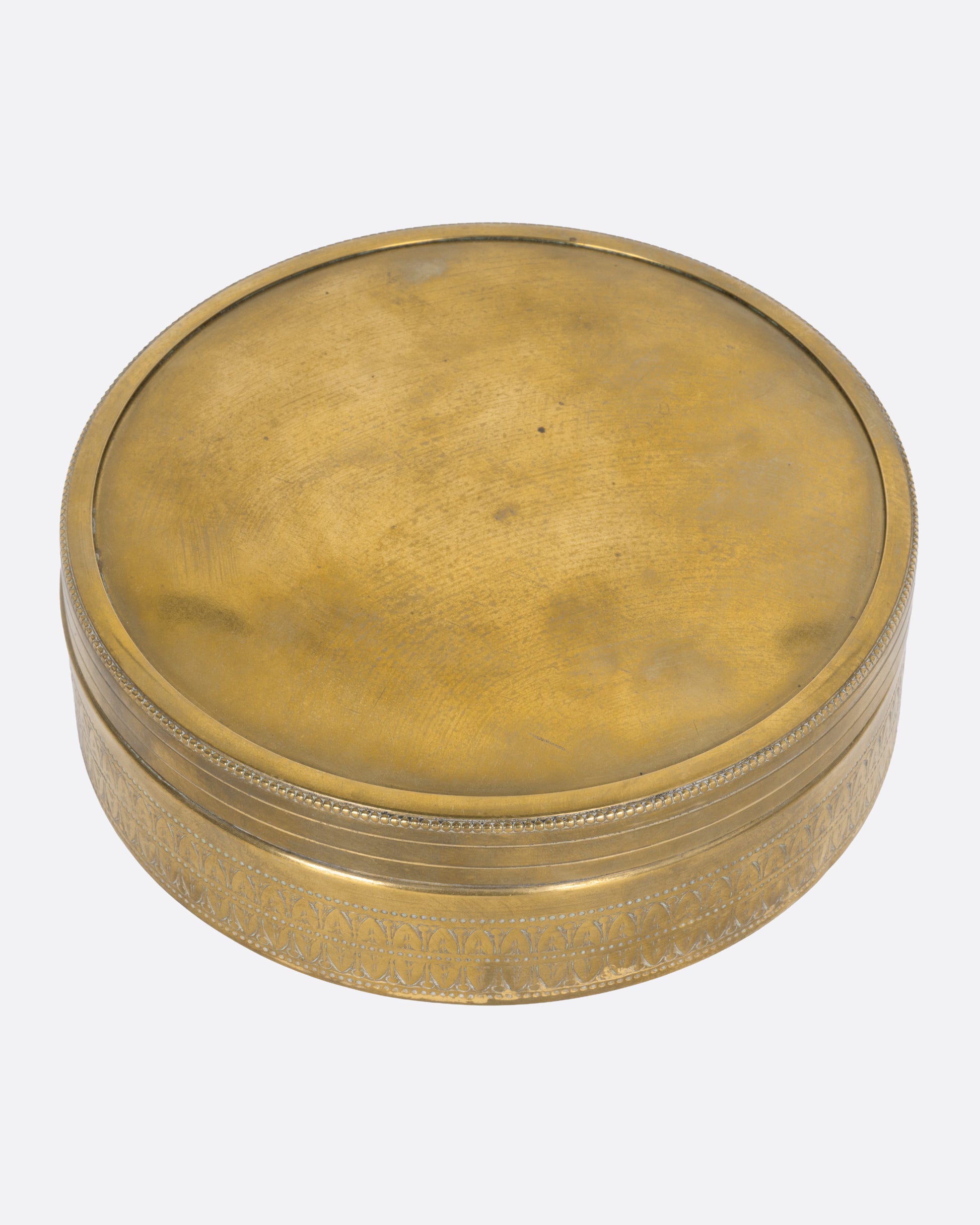 A circular brass box with a lid, shown from the top.