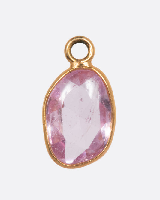 A pink sapphire slice dangle set in yellow gold with a yellow gold bail. Shown from the front.