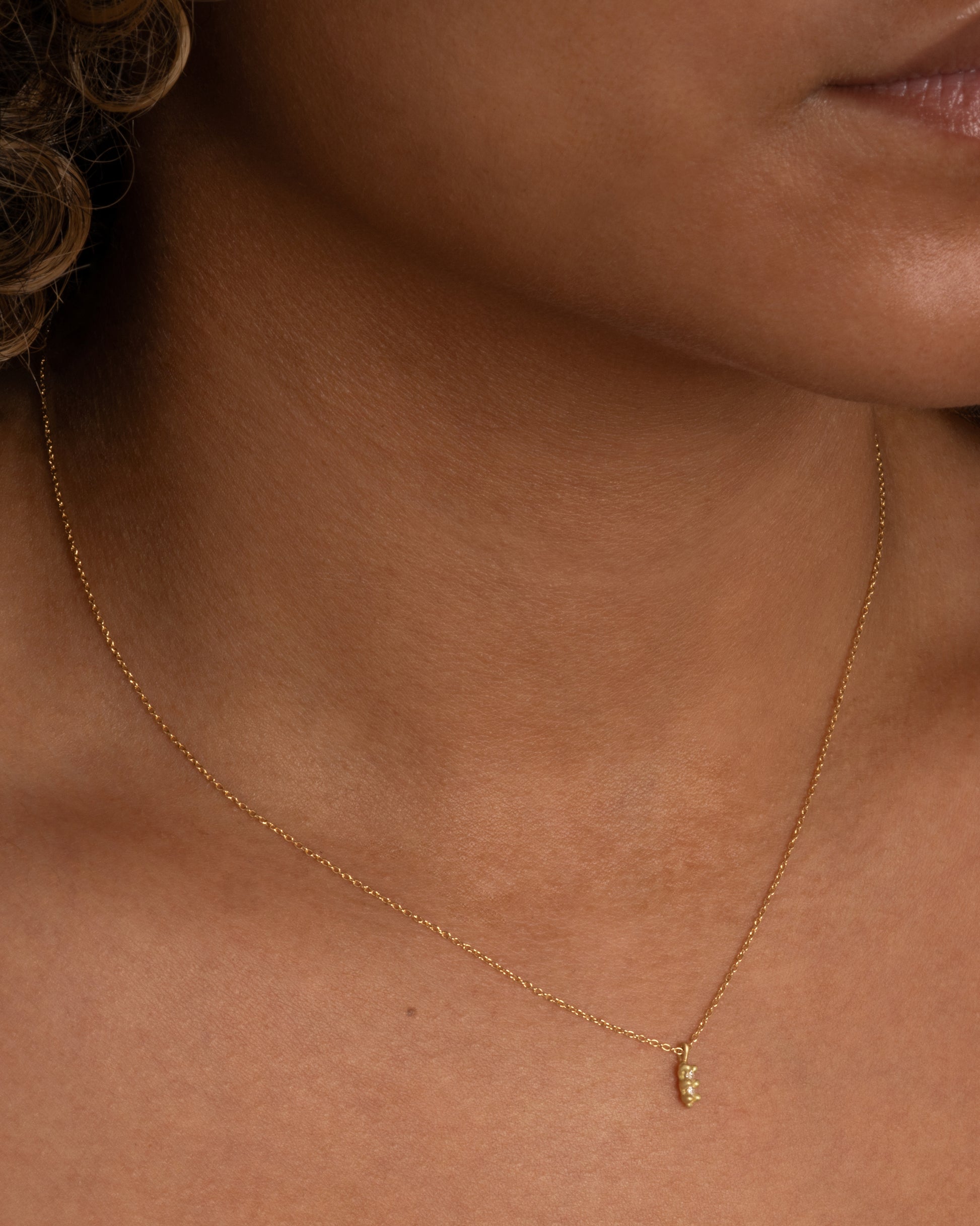 A yellow gold necklace with a double white diamond pendant. Shown worn around the neck.