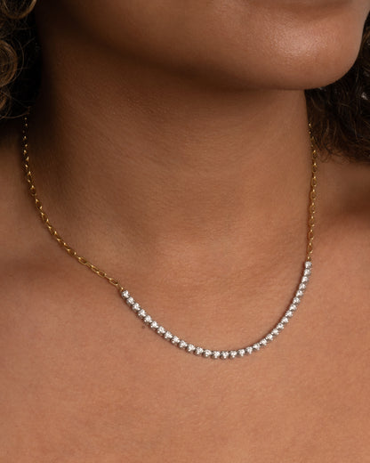 A yellow gold, oval link chain necklace with four inches of contrasting white diamonds. Shown worn around the neck. 
