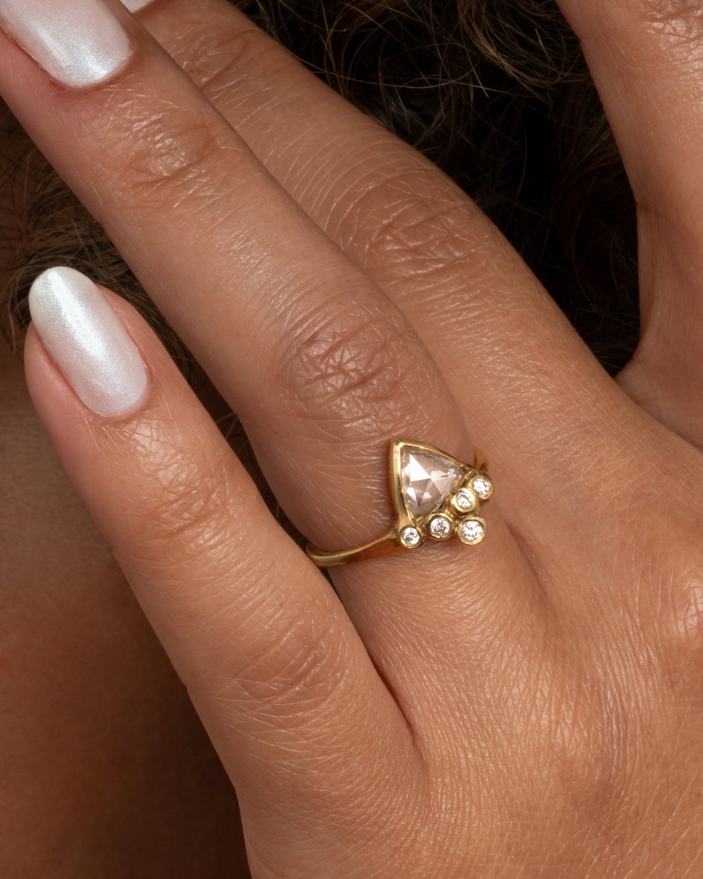 18k yellow gold anemone ring with triangular rose cut diamond and five round diamonds by Kimberlin Brown, shown worn on a finger.