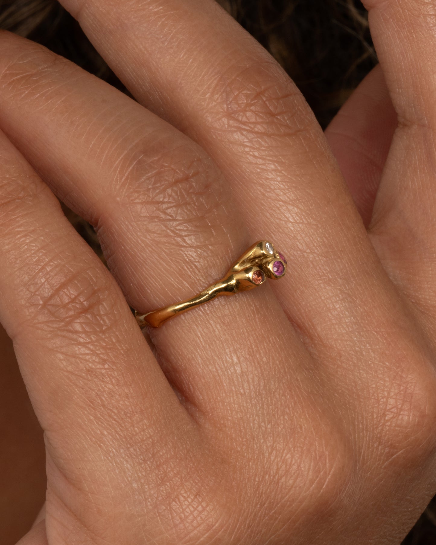 18k yellow gold teeny sea anemone ring with pink sapphires, orange sapphires, and diamonds by Kimberlin Brown, shown worn on a finger.