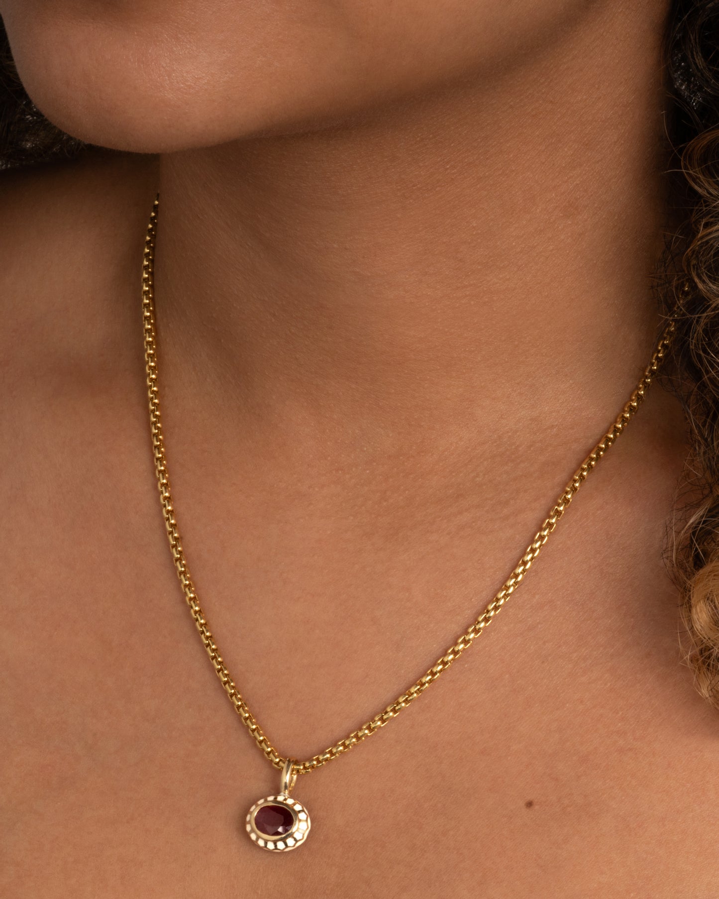 yellow gold ruby pendant with enamel shown worn around the neck
