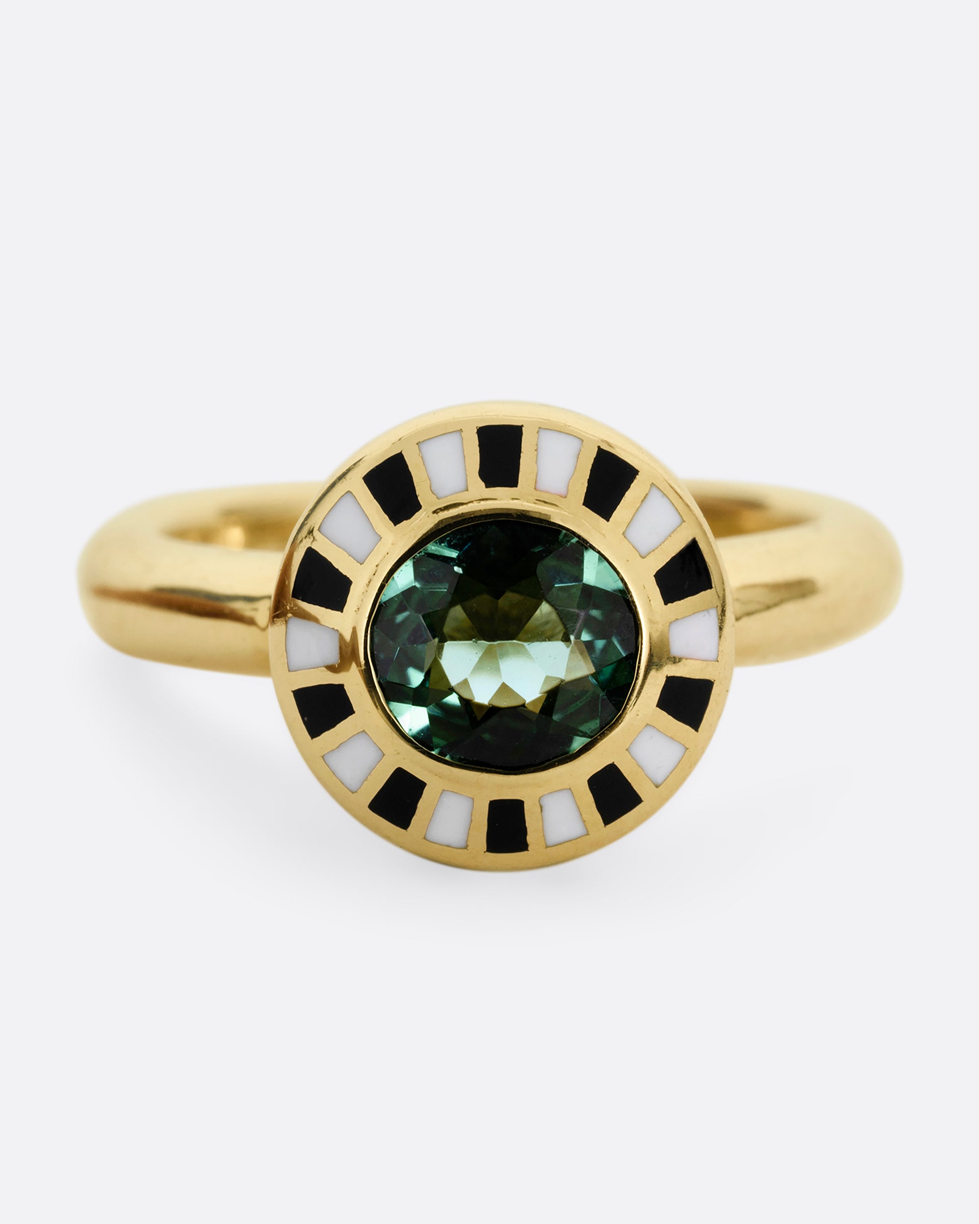 A yellow gold ring with an enamel black and white checkerboard pattern framing a green tourmaline. Shown from the front. 