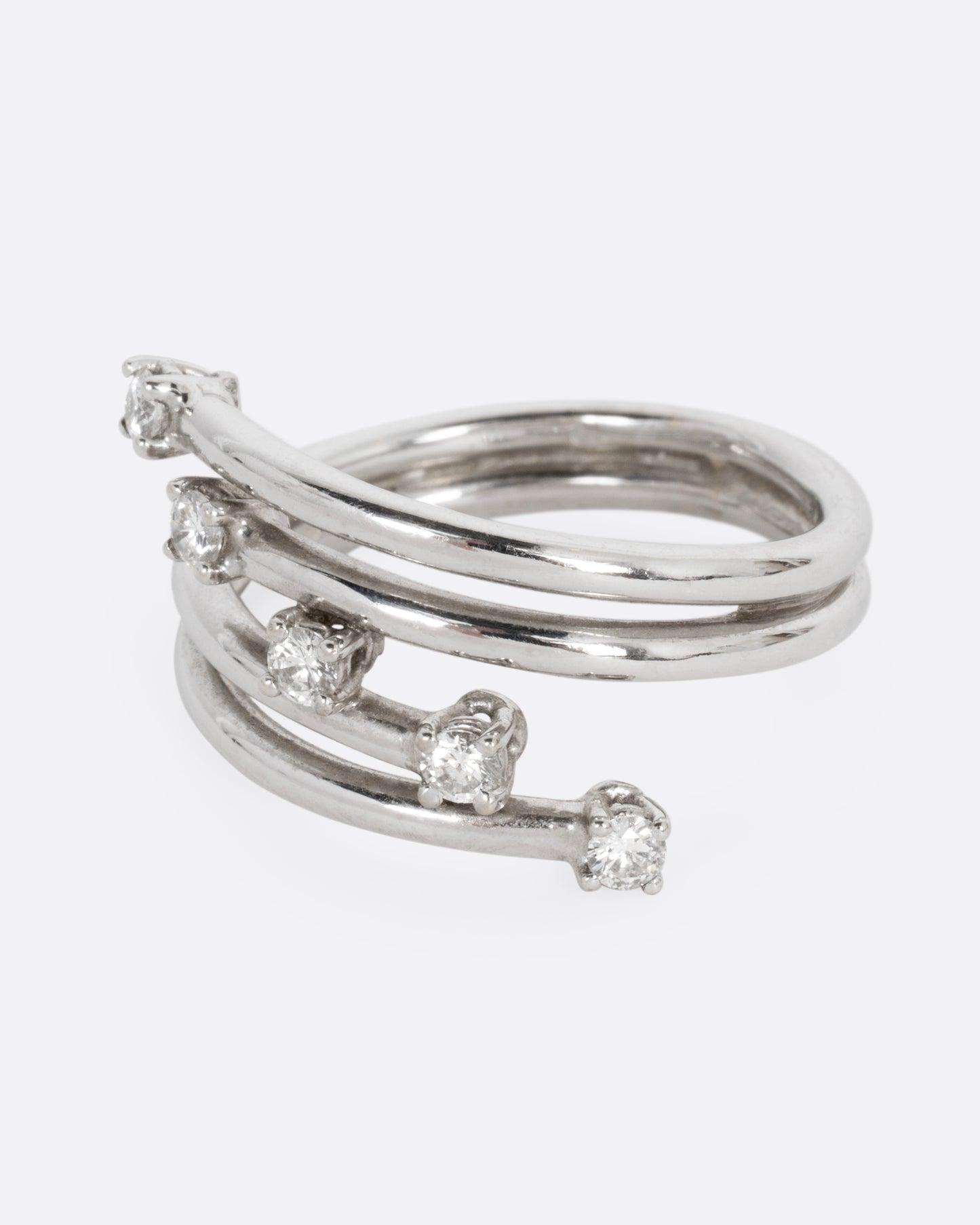 A white gold wrap ring with five diagonal prong set diamonds, shown from the side.