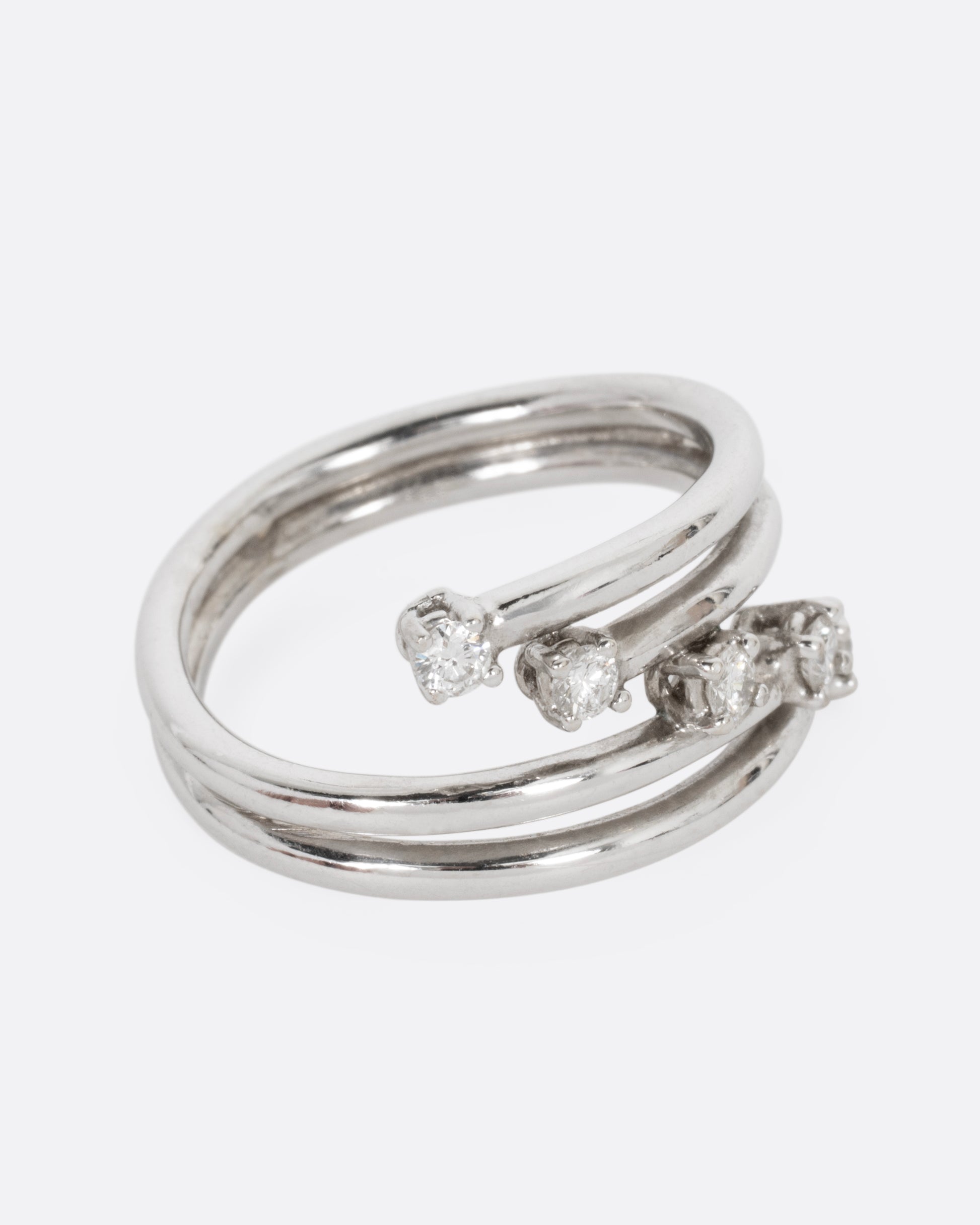 A white gold wrap ring with five diagonal prong set diamonds, shown from the side.
