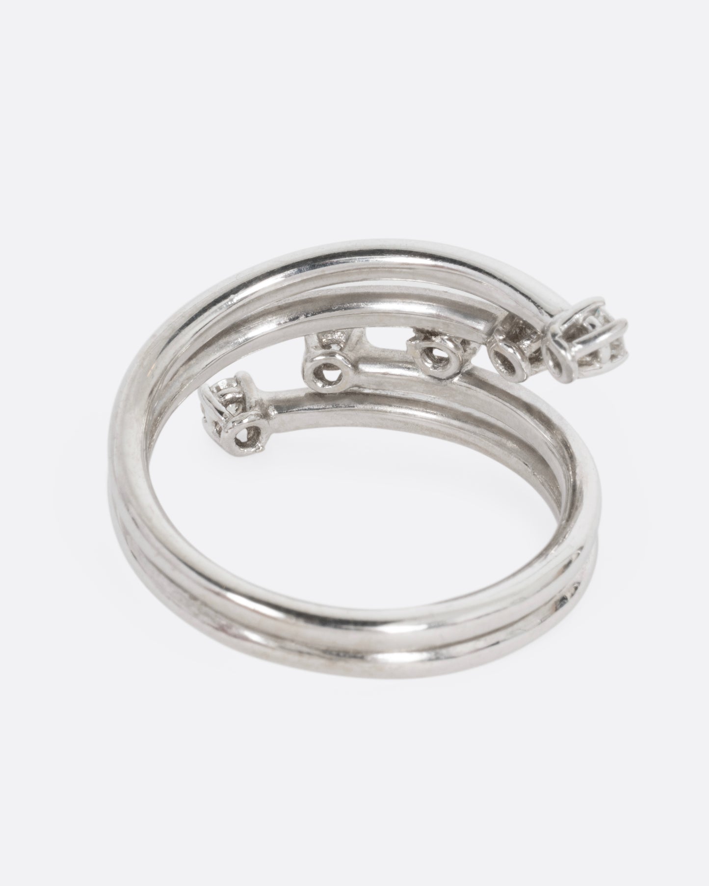 A white gold wrap ring with five diagonal prong set diamonds, shown from the back.
