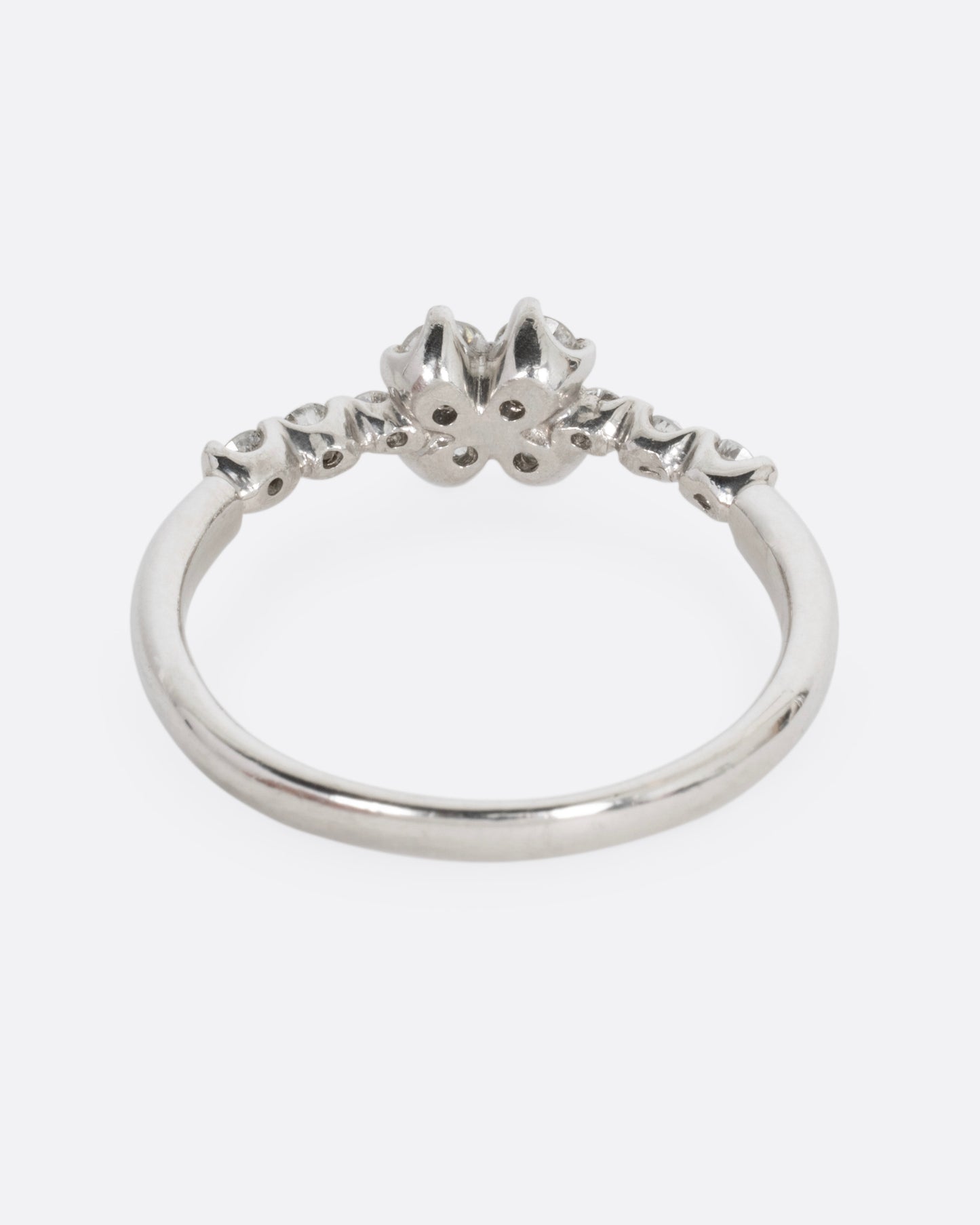 A platinum ring with an 'X' shape and diamonds, shown from the back.