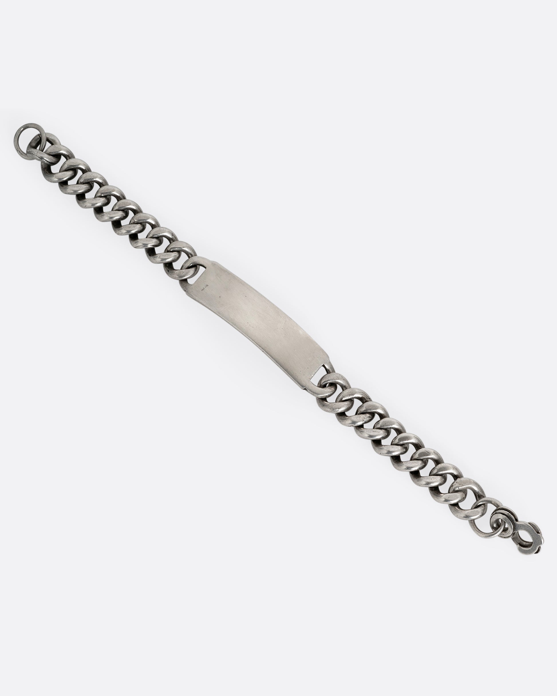 A silver curb chain ID bracelet, shown from the front open.