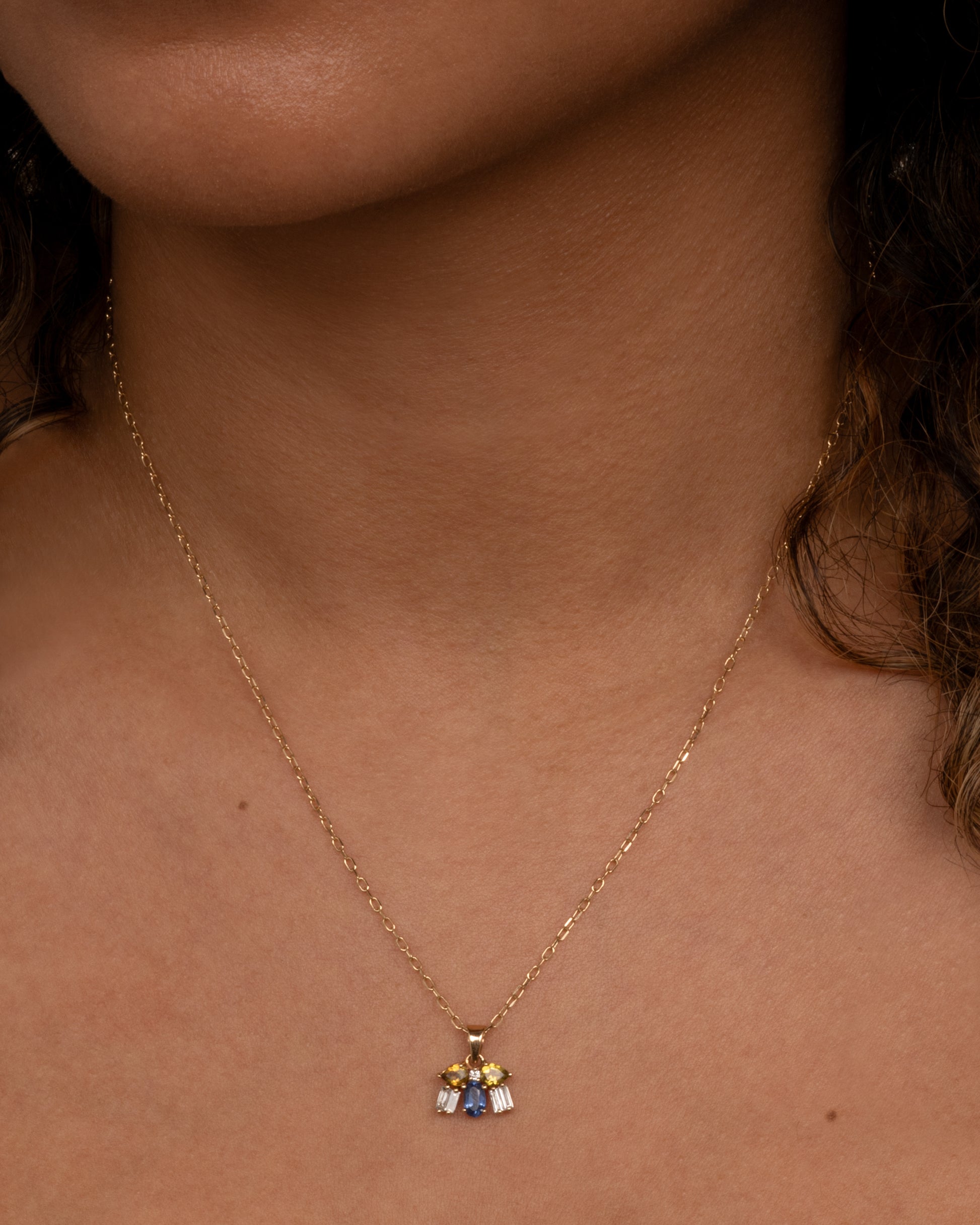 A yellow gold necklace with a winged bug pendant made of tourmalines, kyanite and diamonds. View shown worn around the neck.