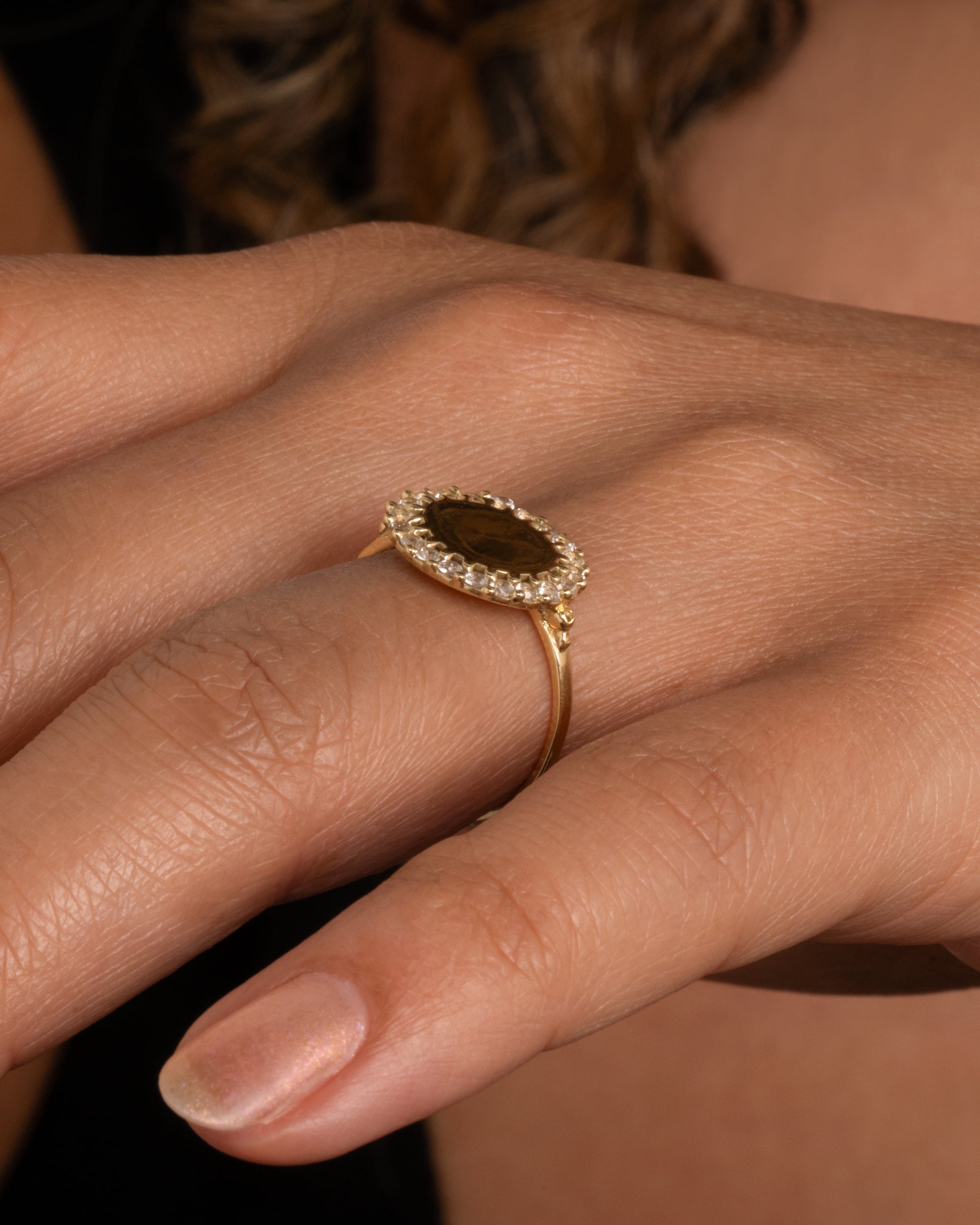 A 14k gold circle ring with a white diamond halo. Shown worn on a hand.