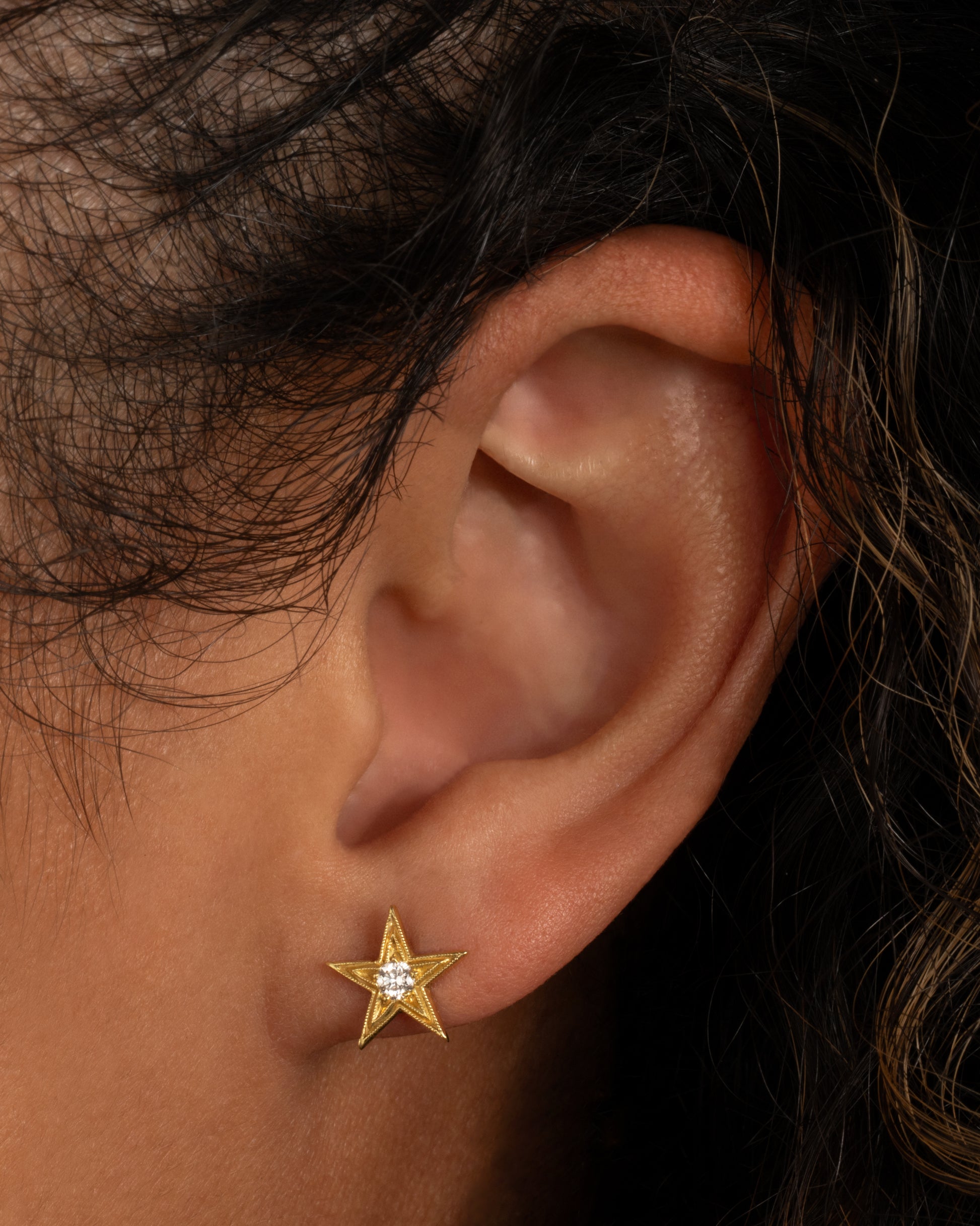 This earring is one of the many varieties of stars in Anthony Lent's work, this time a bit larger and more traditional. Shown worn in an ear.