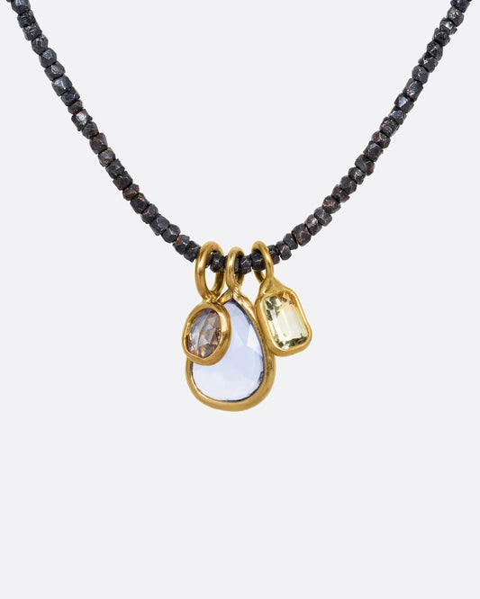 A necklace with oxidized silver Hill Tribe beads and a cluster of blue and green sapphires and a rose cut diamond. Shown from the front.