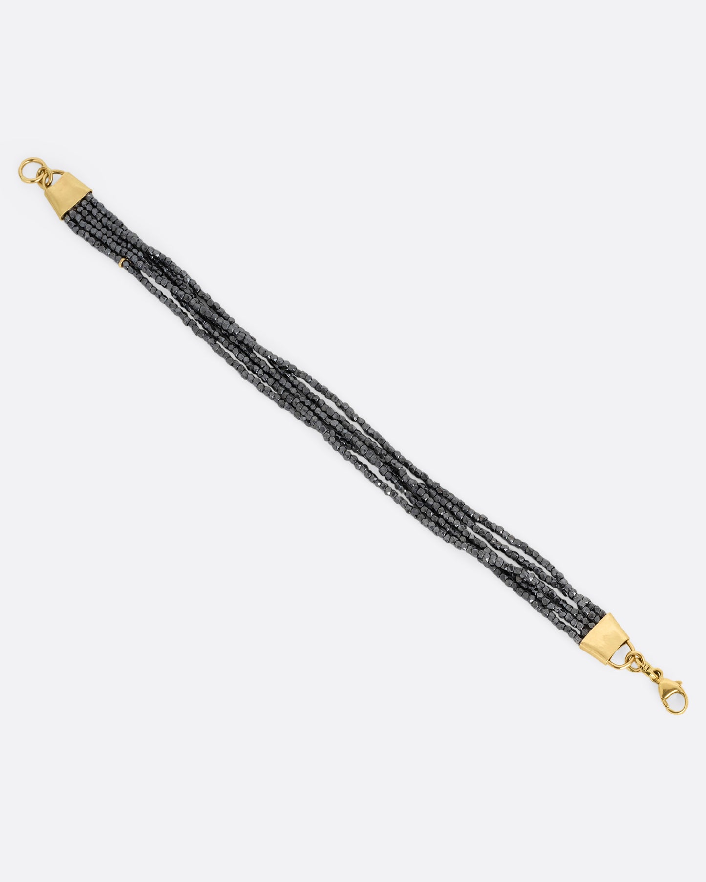A bracelet with five strands of oxidized silver beads converging at  yellow gold capped ends with a lobster clasp. Shown open from the top.