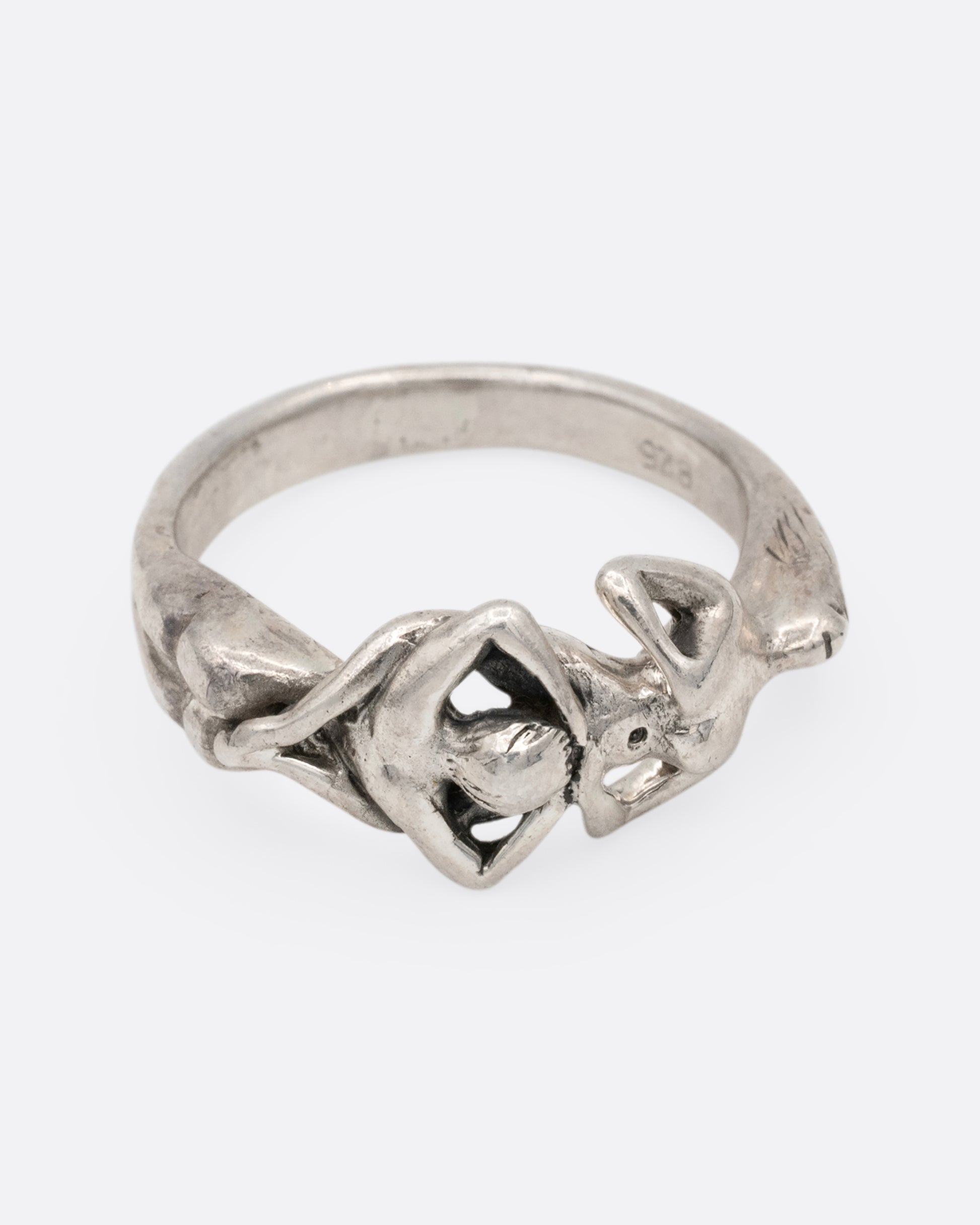 A silver ring with an erotic couple. Shown from the front.