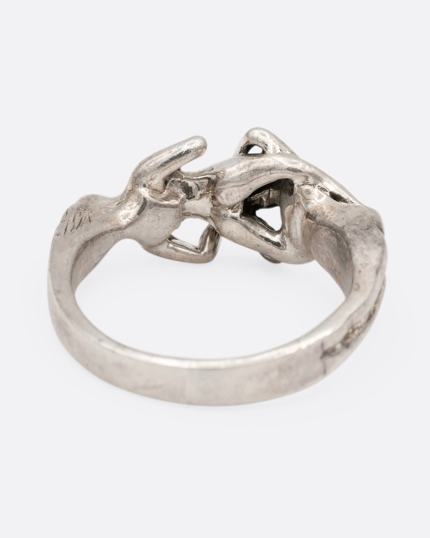A silver ring with an erotic couple. Shown from the back.