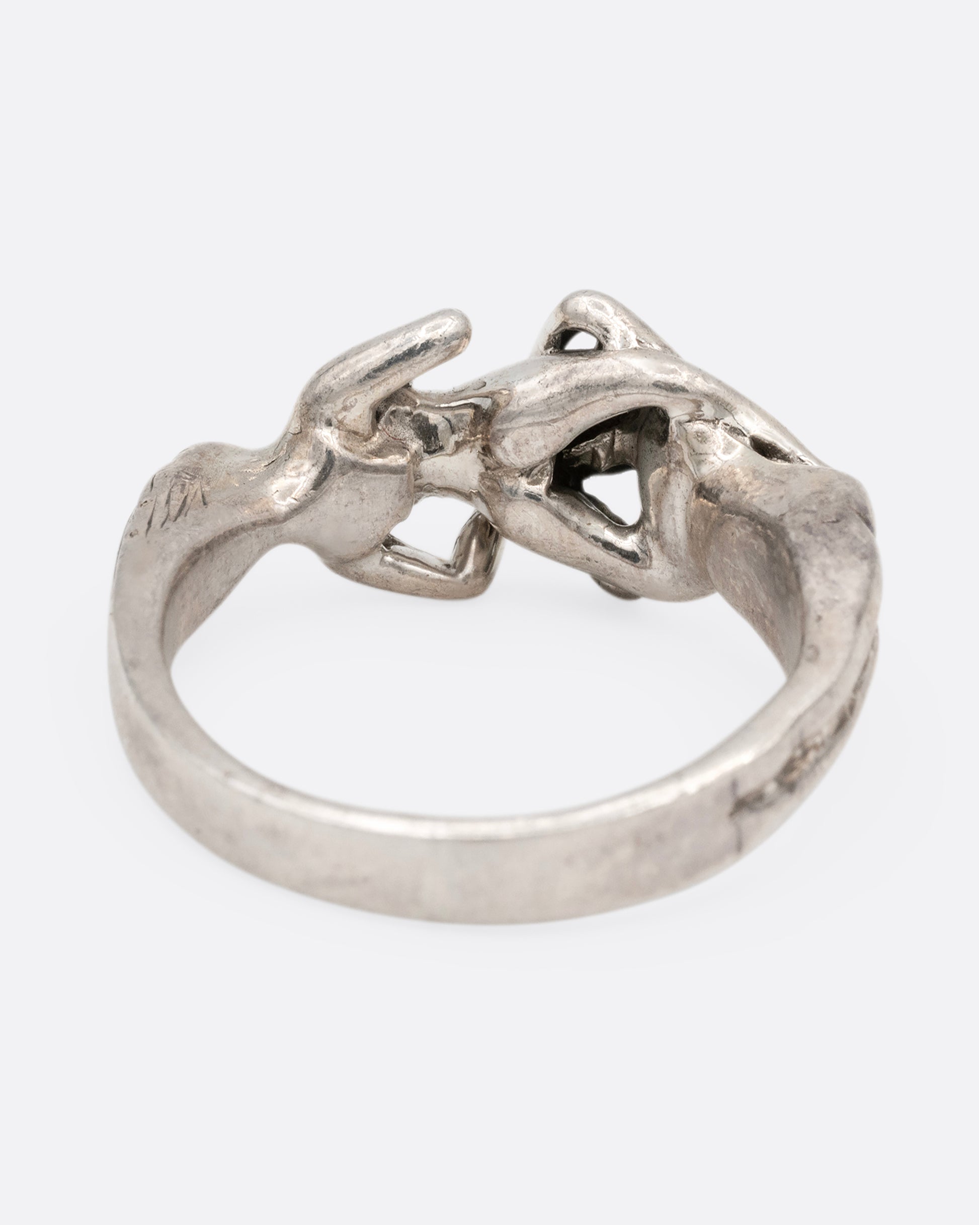 A silver ring with an erotic couple. Shown from the back.