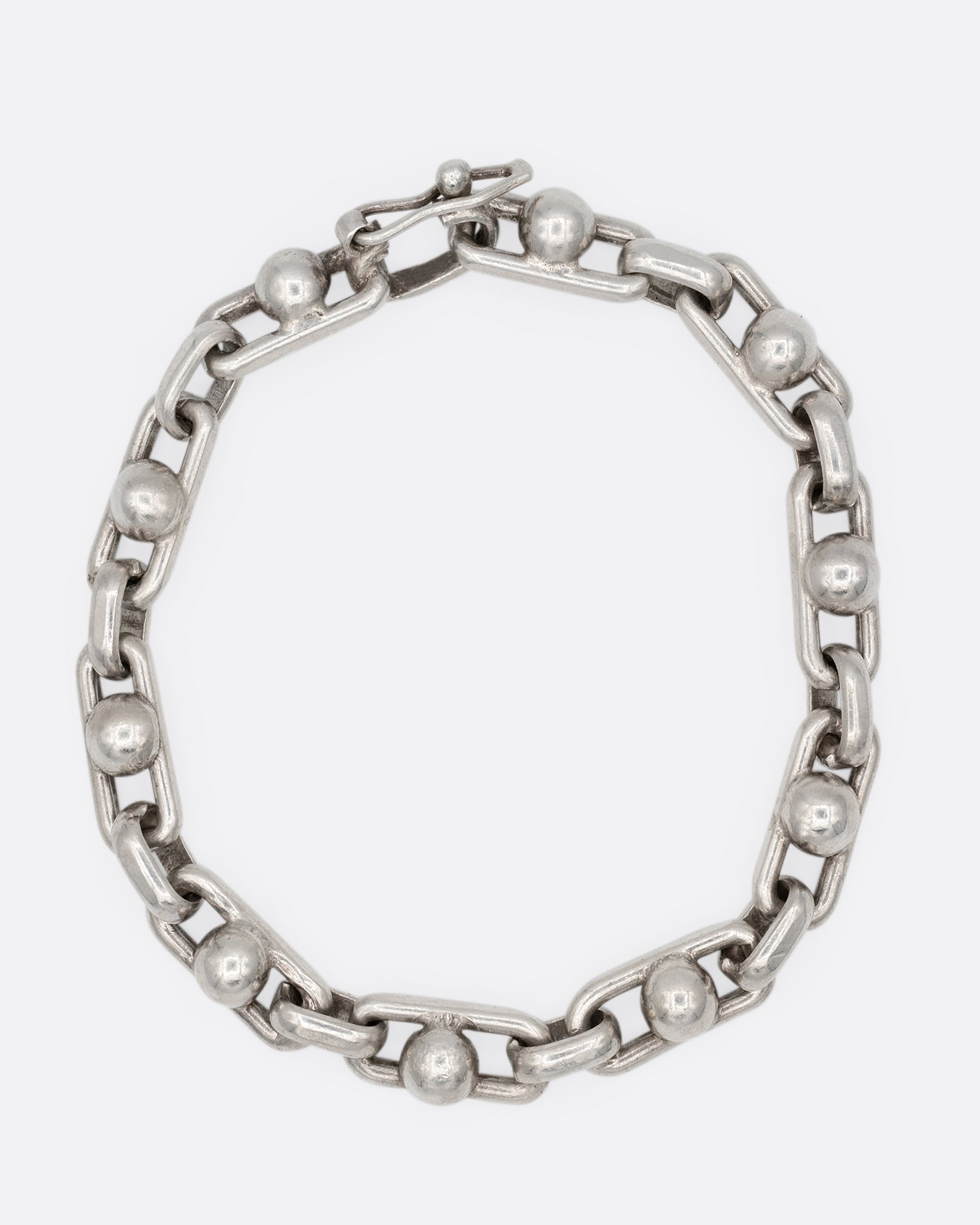 A silver bracelet with spheres at the center of each link. Shown from the front.