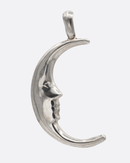 A silver crescent moon charm with a face. Shown from the front.