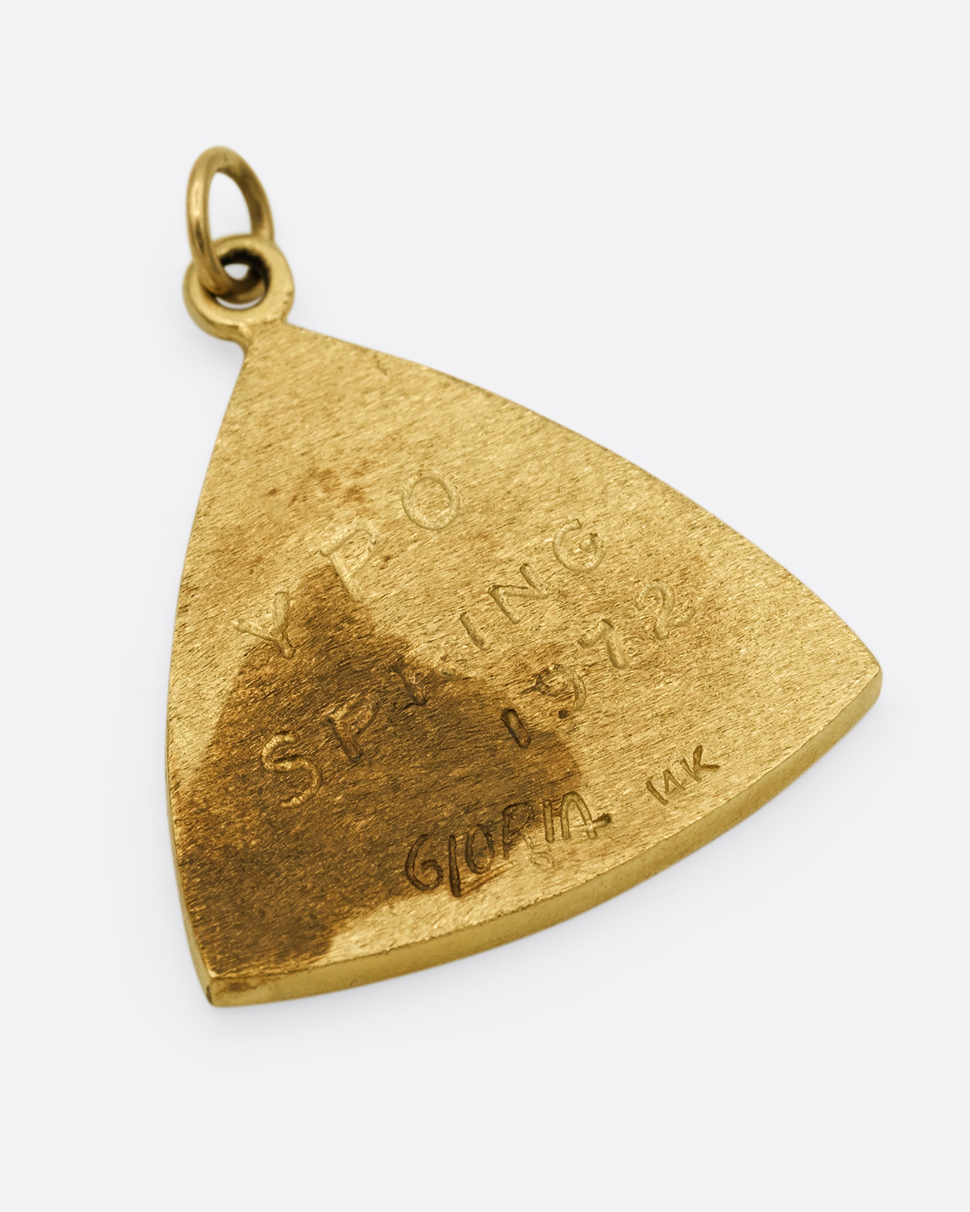 A yellow gold triangular charm with a bird getting worm on the front. Shown from the back.