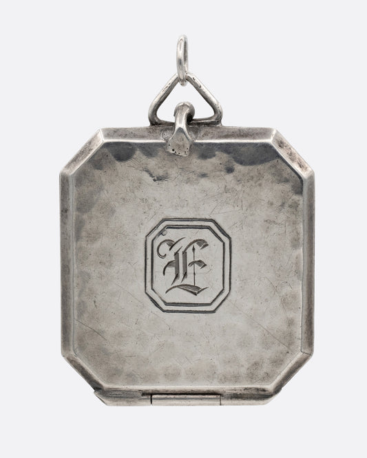 A silver octagonal locket with an 'E' engraved a its center. Shown from the front.