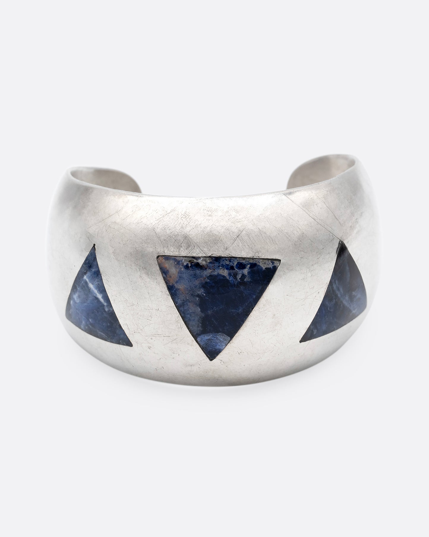 A broad silver cuff with three large lapis triangles along its convex front. Shown from the front.