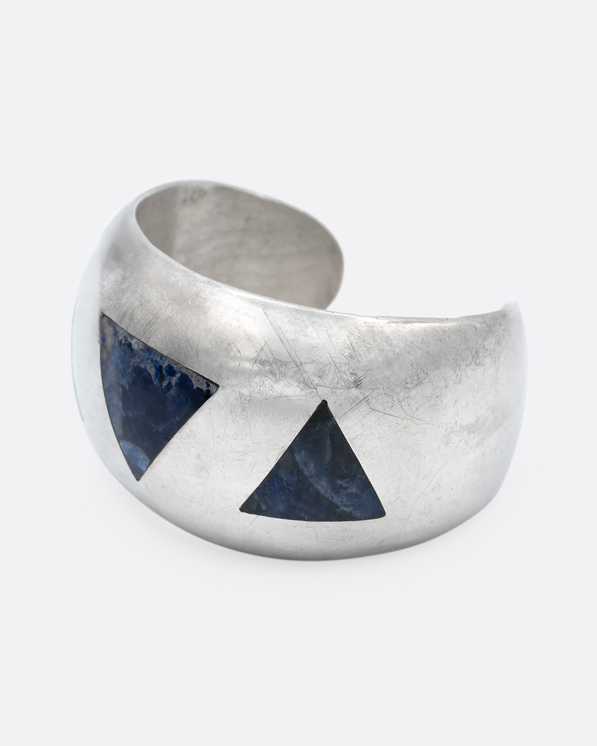 A broad silver cuff with three large lapis triangles along its convex front. Shown from the side.