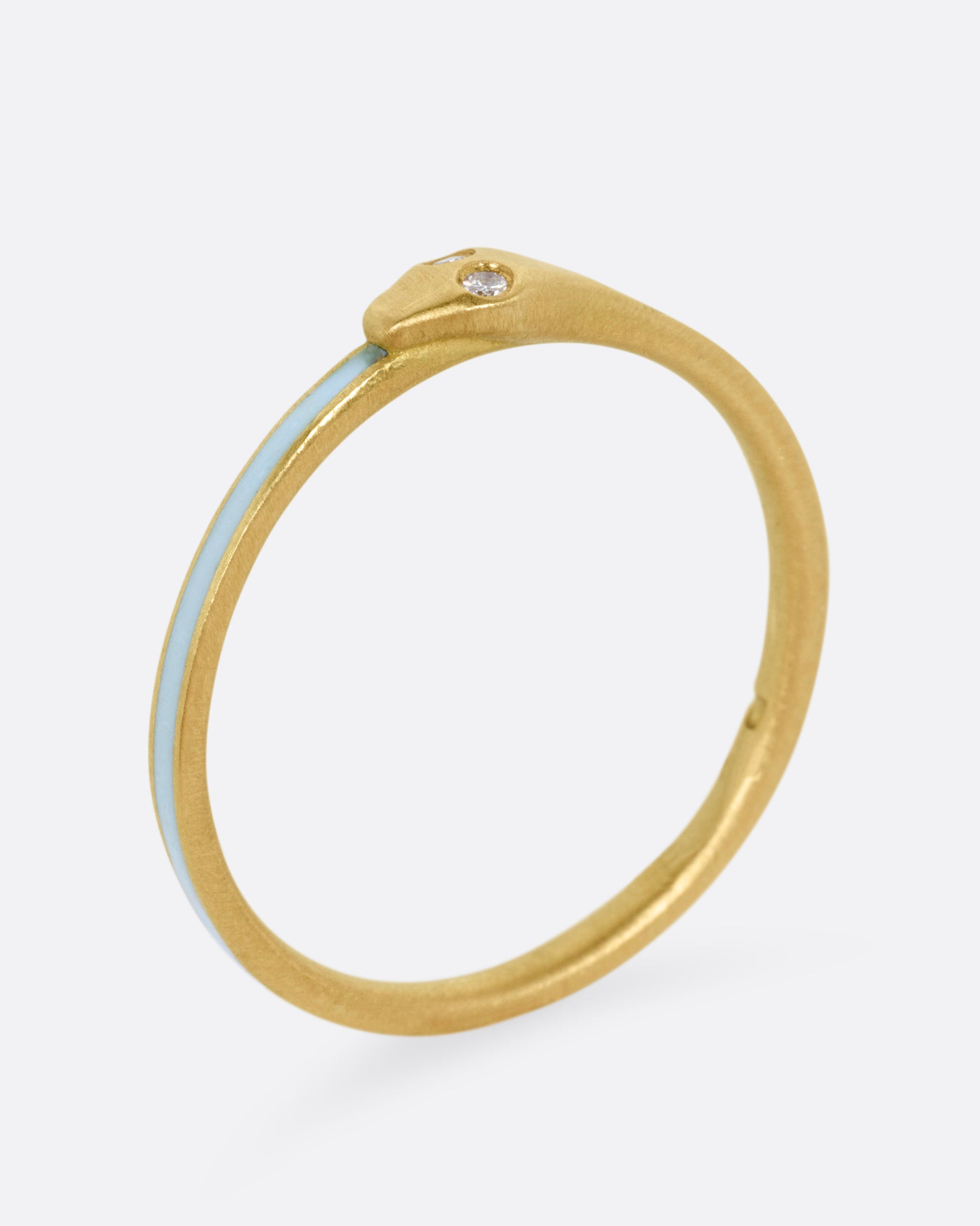 A yellow gold ouroboros ring with diamond eyes and light blue enamel, shown from the side standing up.