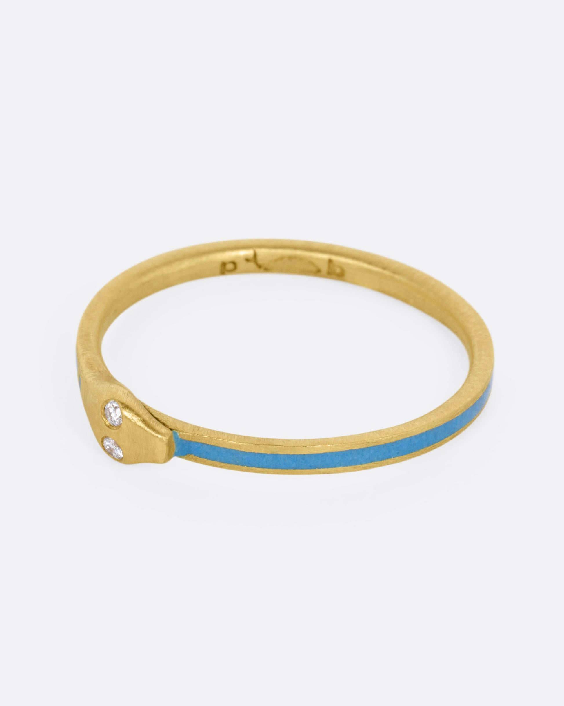 A yellow gold ouroboros ring with diamond eyes and pale blue enamel, shown from the side. 