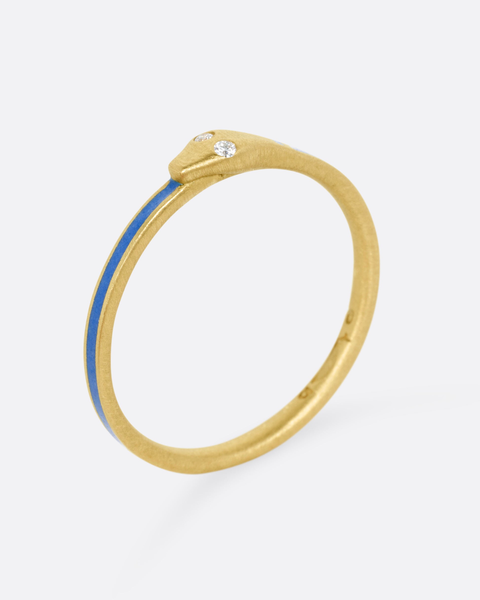 A yellow gold ouroboros ring with diamond eyes and blue enamel, shown standing up from the side. 
