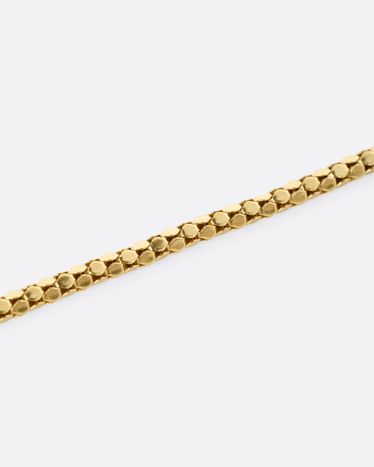 A close up of a yellow gold tube chain necklace.