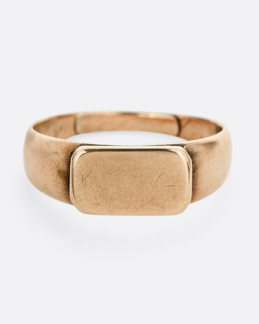 A yellow gold signet ring with a rectangular face. Shown from the front.