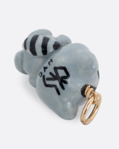 A hand painted raccoon charm with a bow tie. Shown from the back.