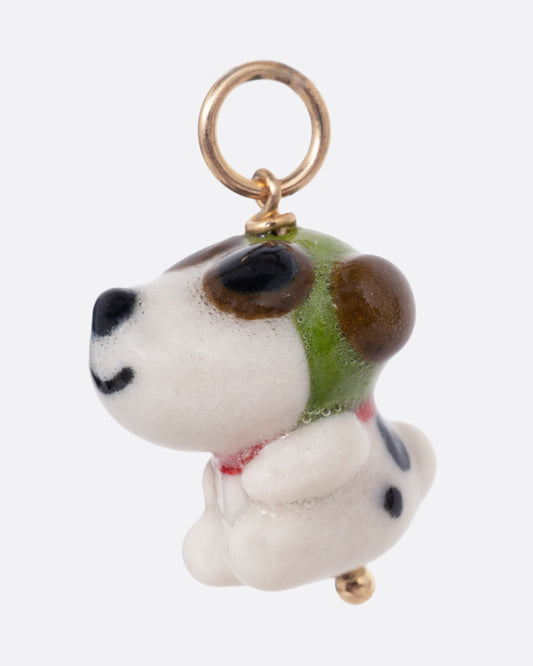 A porcelain Snoopy charm with flight goggles and hat. Shown from the side.
